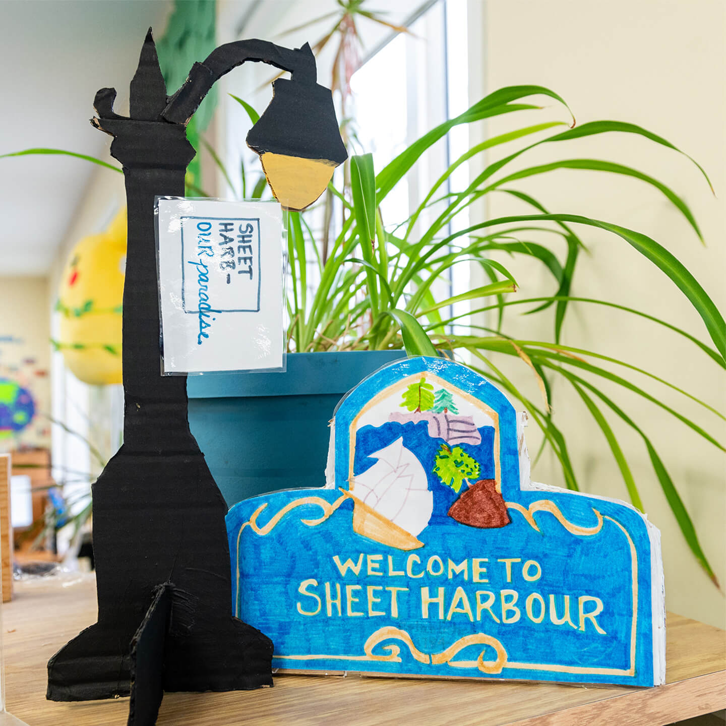 Hand made art piece on a desk that is a lamp post and welcome to sheet harbour sign